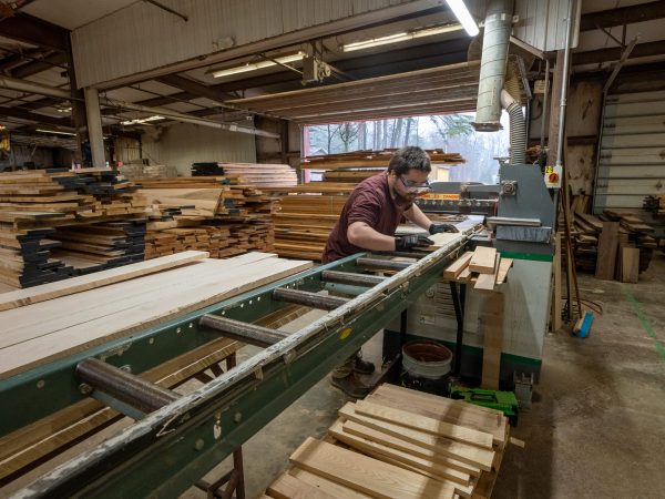 worker wearing goggles and gloves holding piece of lumber